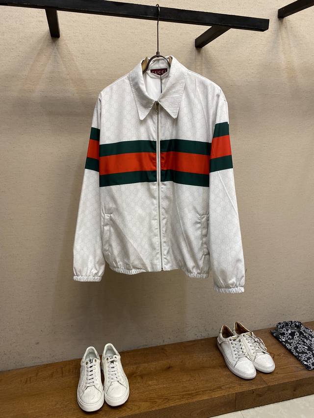 Gucci、2024春夏新品平稳尼龙夹克 这款夹克采用蓝色平纹尼龙材质，让人联想到复古运动服。灵感源自80年代复古印花的品牌织带继续以出人意料的方式呈现，休闲宽