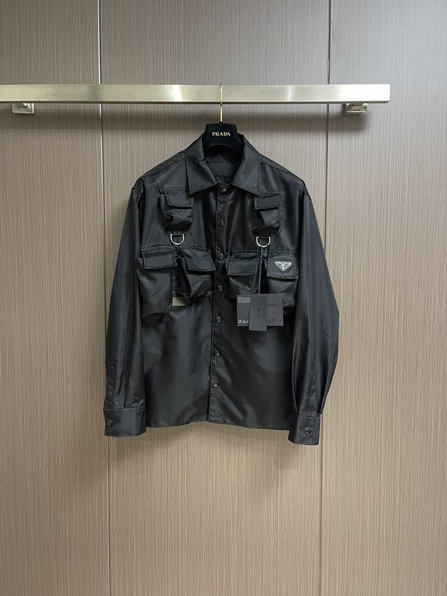 Prada 24Ss 工装尼龙衬衫外套 选用标志性的创新再生尼龙 Re-Nylon 打造 搭配保龄球领 彰显实用而现代的风采 小巧实用的口袋为设计锦上添花 提升