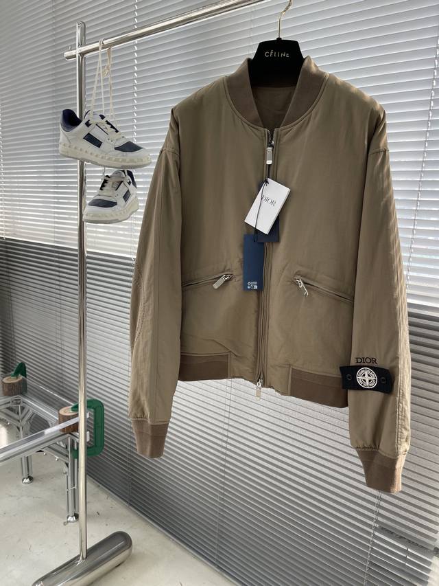 Dio X Stone Island 联名星辉罗盘飞行夹克 设计以黑色电力纺丝绸混纺制成，采用舒适剪裁并配以拉链开合，此款缀以肘部饰片刺绣，衣袖则饰有dio标志