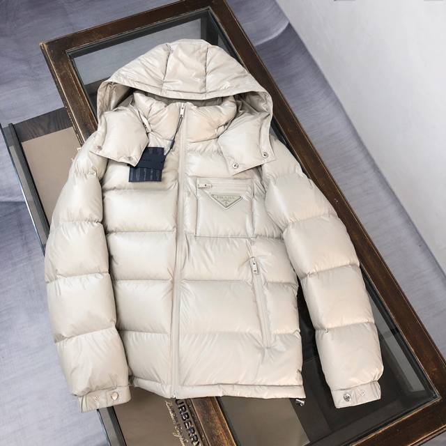 Prada 普拉达 2024秋冬最新款亮面羽绒服！前胸口袋饰有品牌独特△三角金属铁标徽章 甄选客供100%棉纶材质制作而成，面料拥有极为优越的防水透气性，能抵挡