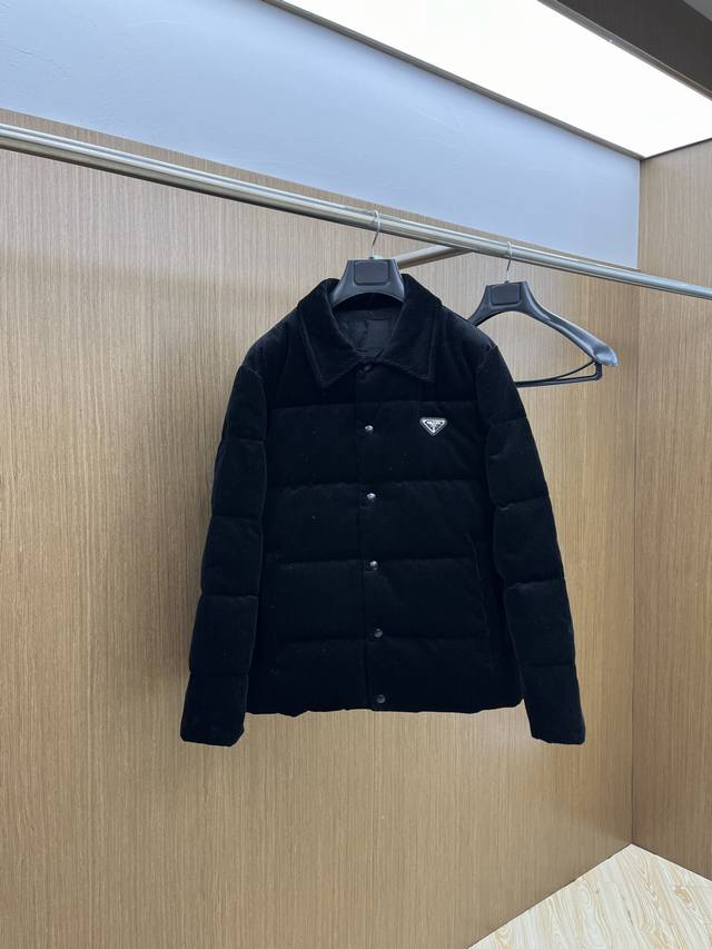 Prada 24Fw 灯芯绒立领羽绒服 这款短裁灯芯绒羽绒 蕴藉prada的混搭个性 金属三角形徽标展现标志性元素 灯芯绒为生产痛点 所产生的 面料光差 顺毛差