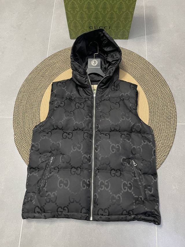 上新 Gucci Fw新款双g满logo黑色连帽马甲、这款拉链羽绒服是焕新推出的配饰和成衣系列中的一款 再生尼龙由可回收利用的缝纫线和辅料制成，依托灰色背景突显